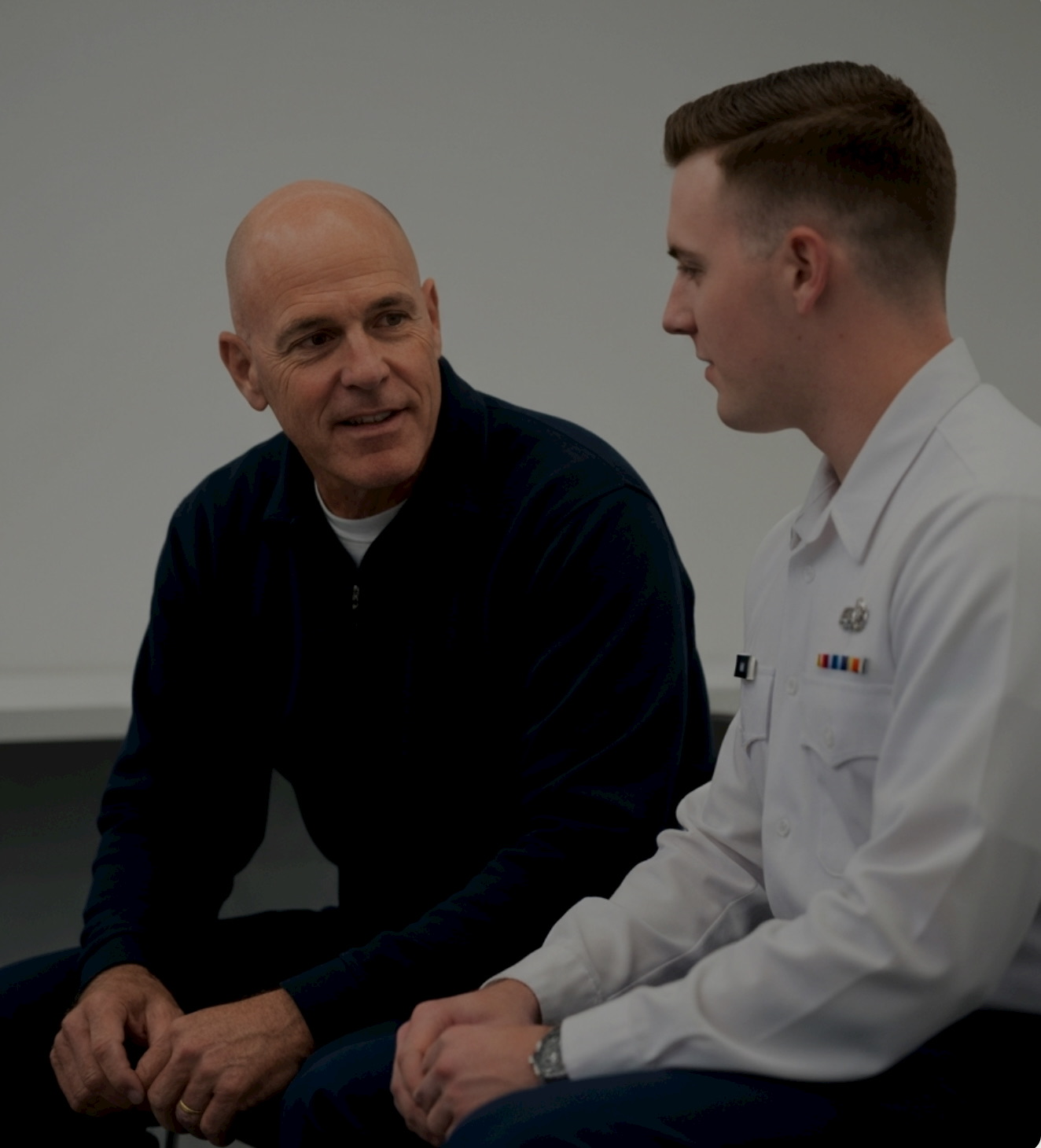 An older veteran speaking with a younger service member